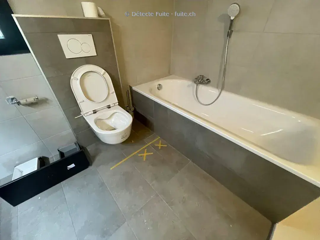 Salle de bains avec un repère au sol près de la baignoire